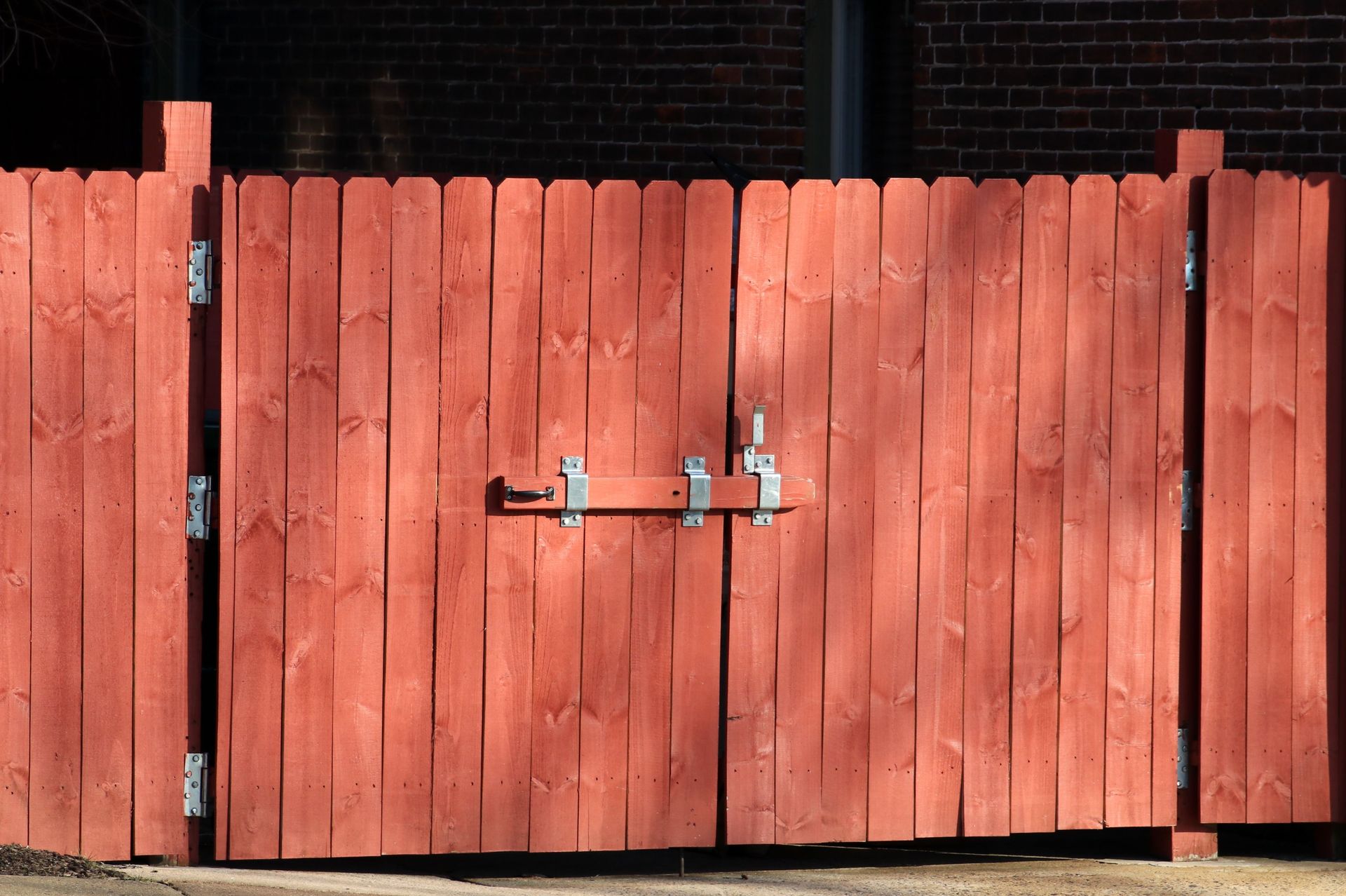 Rustic red wooden fence with a metal latch, ensuring safety and security outdoors.