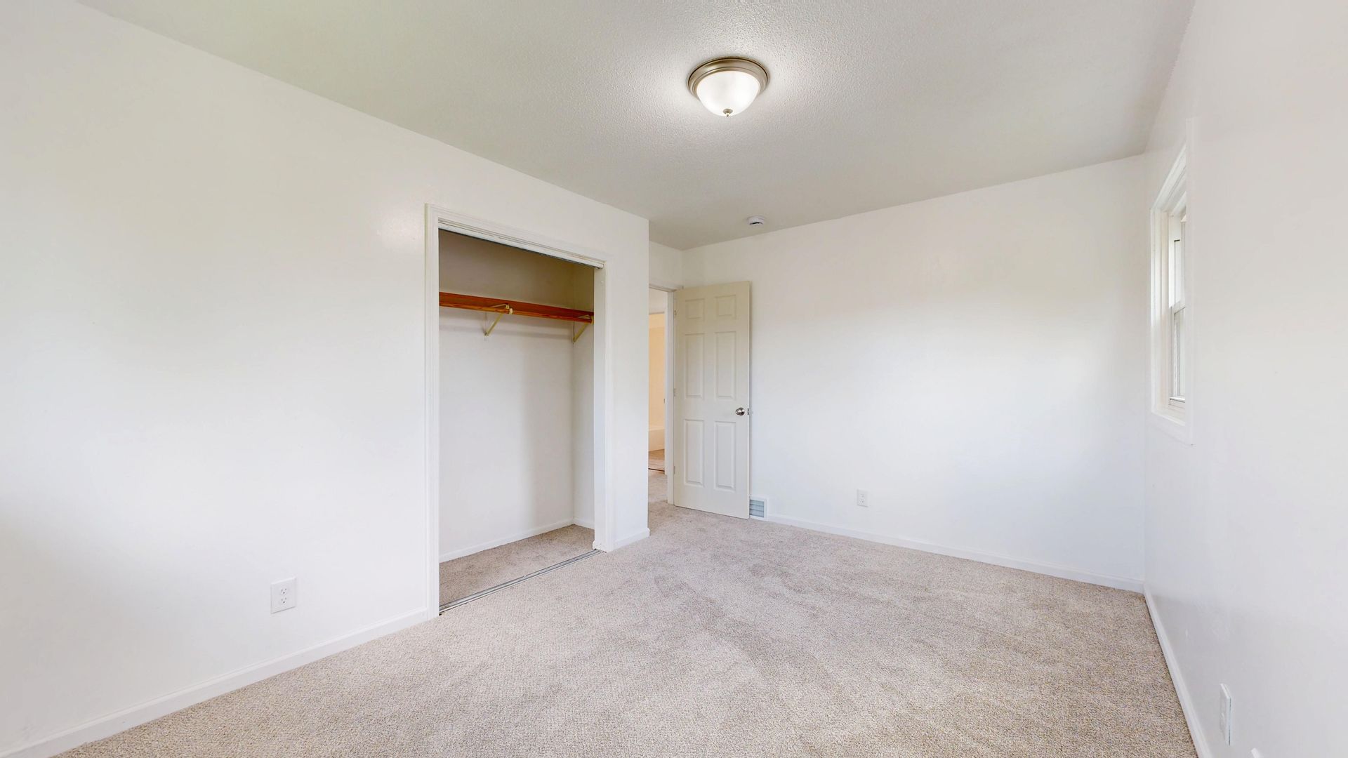 Spacious, empty room with plush carpet and open closet, well-lit